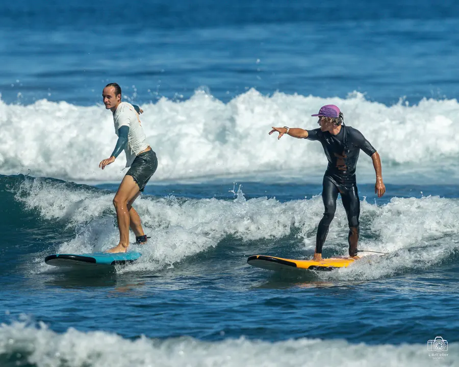 Cours particulier de surf à La Réunion, le moniteur accompagne l'élève vague après vague